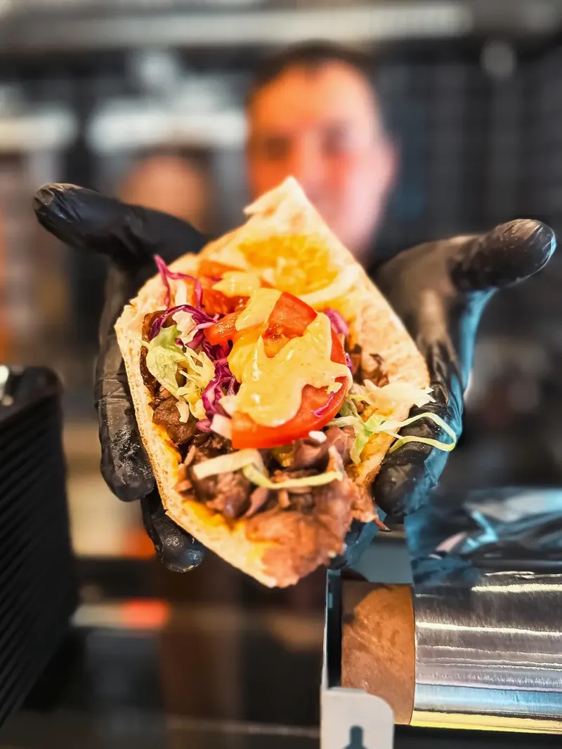 Mitarbeiter reicht einen frisch belegten Döner über den Tresen