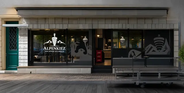 Fassade des Alpenkiez mit Alpenkiez-Schriftzug im Schaufenster